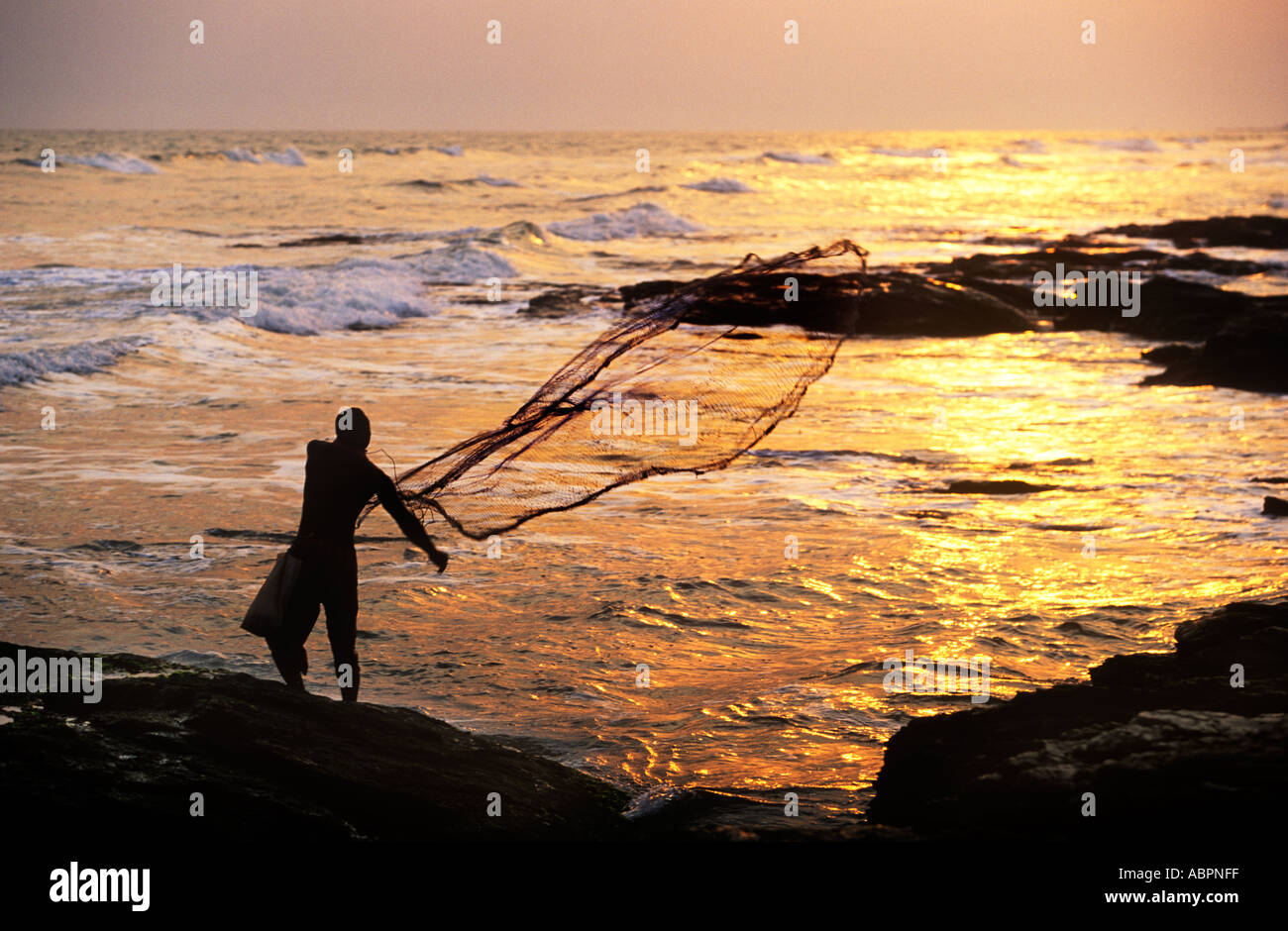 Casting a fishing net from the rocks on Labadi Beach, near Accra Ghana Stock Photo