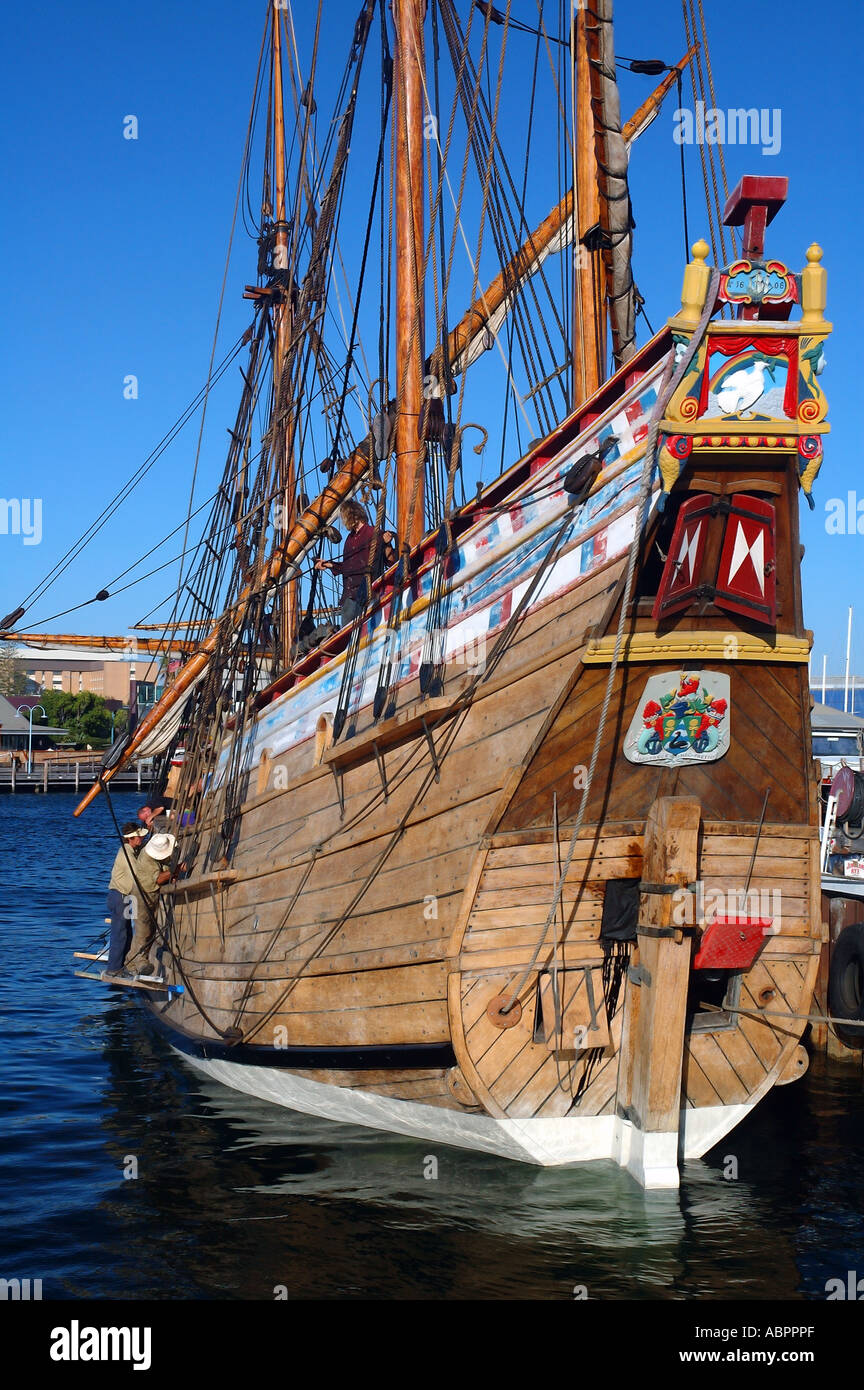 Workmen cleaning and recaulking wooden hull of sailing ship Stock