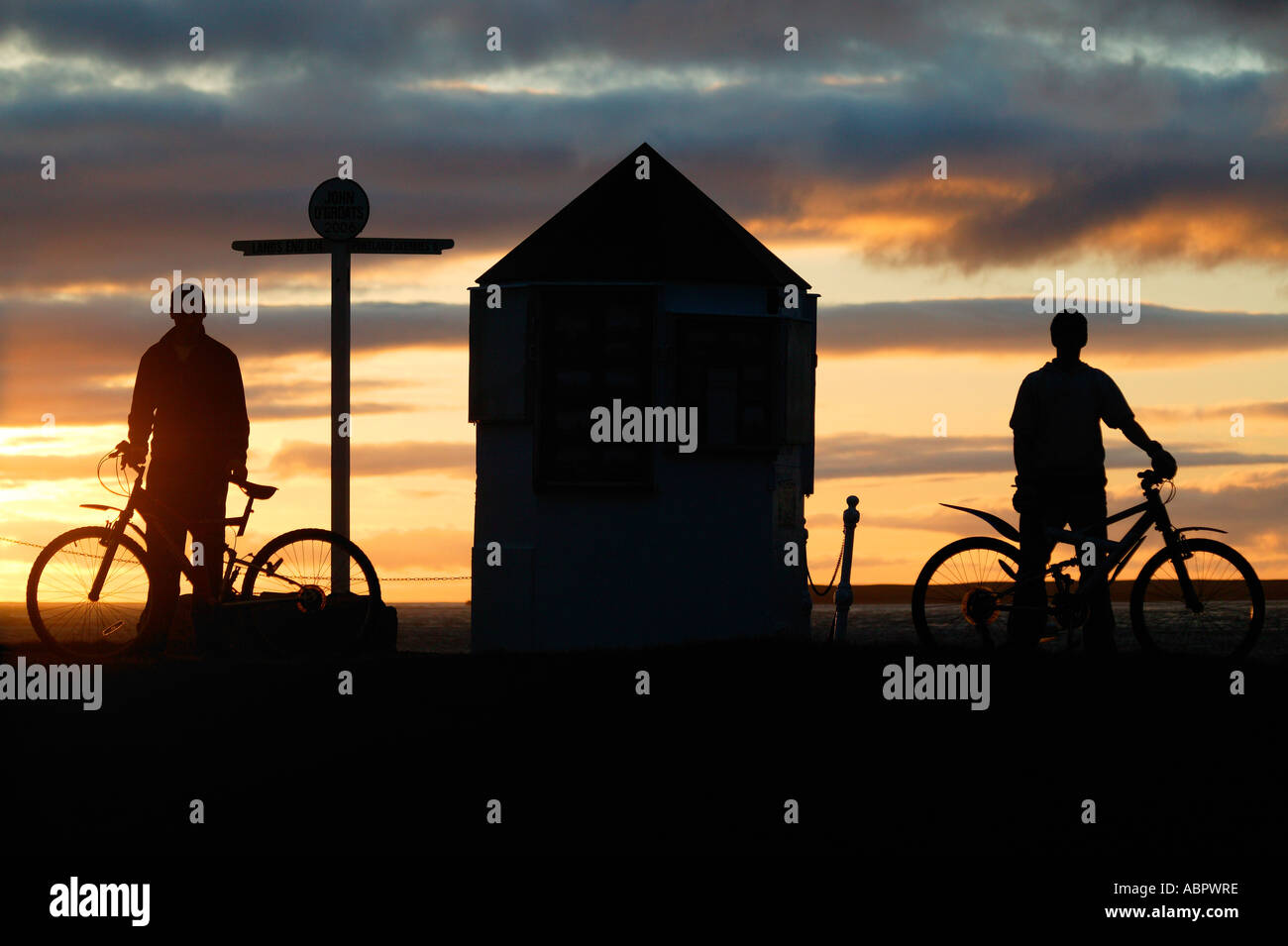 Two boys with bicycles in silhouette at Sunset, John o' Groats Caithness, Highlands, North Scotland UK Europe Stock Photo