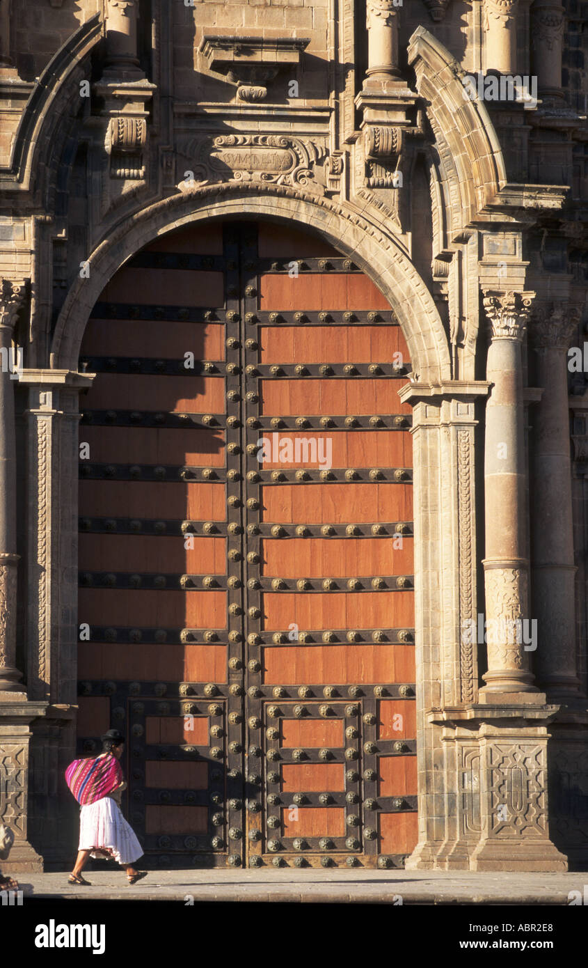 Plaza de Armas, Cusco, Peru. Main door to the cathedral with a woman in traditional dress and bundle walking by. Stock Photo