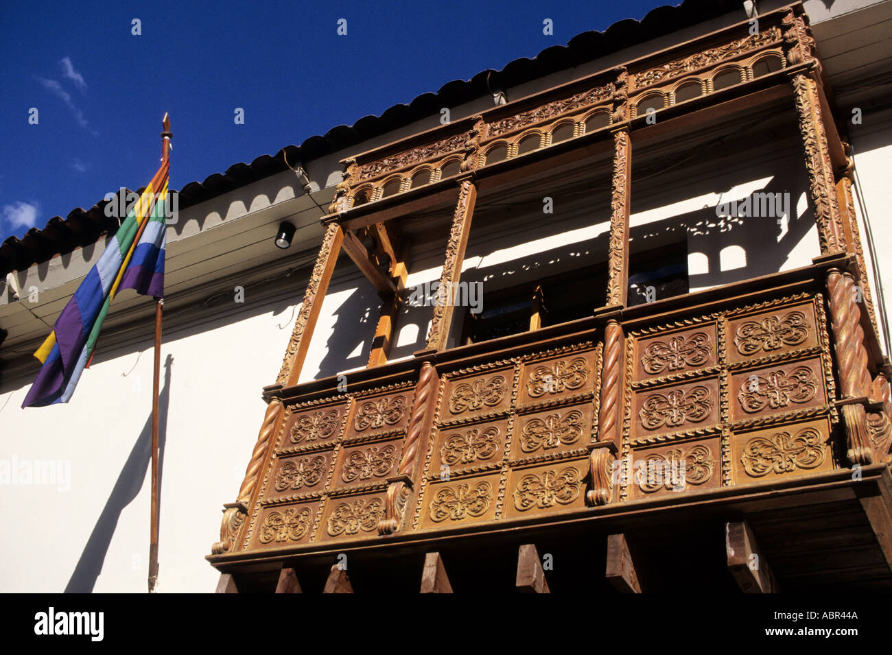 Cusco, Peru. Typical carved wooden balcony with the Cusco rainbow flag. Stock Photo