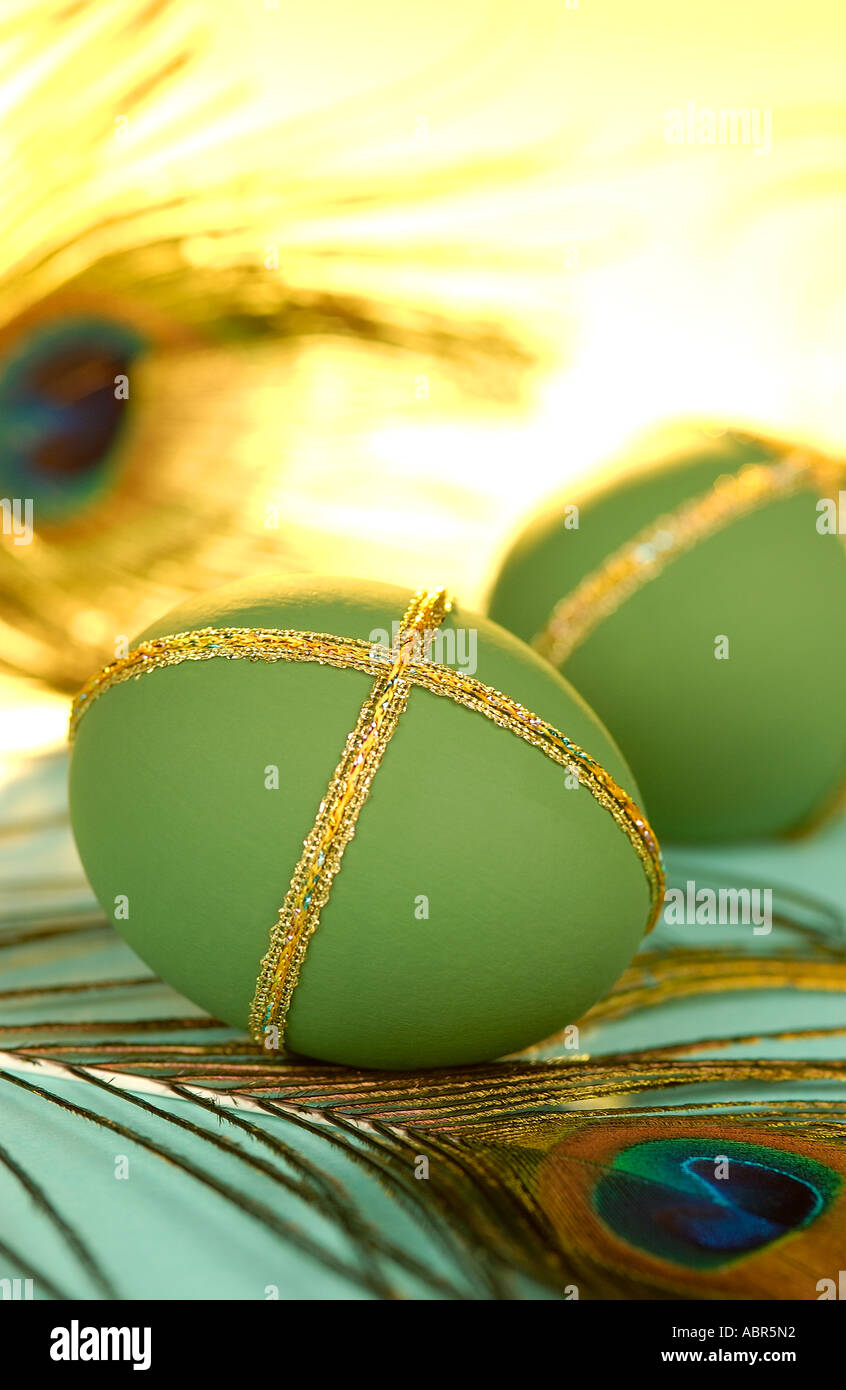 Green decorative eggs on a bed of peacock feathers Stock Photo