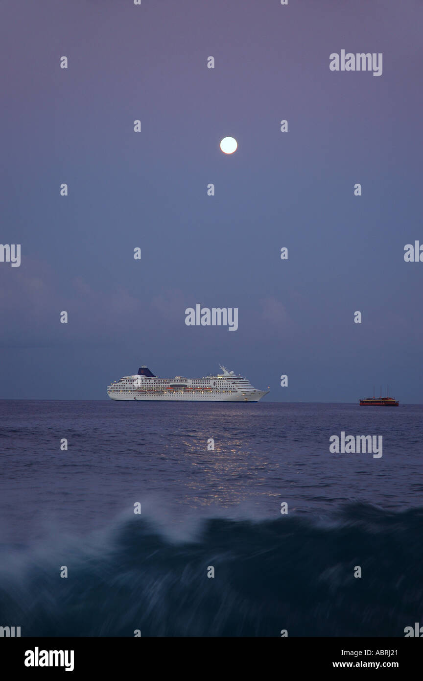 Full moon setting and cruise ship Breaking wave in the foreground Kailua Kona Hawaii Stock Photo