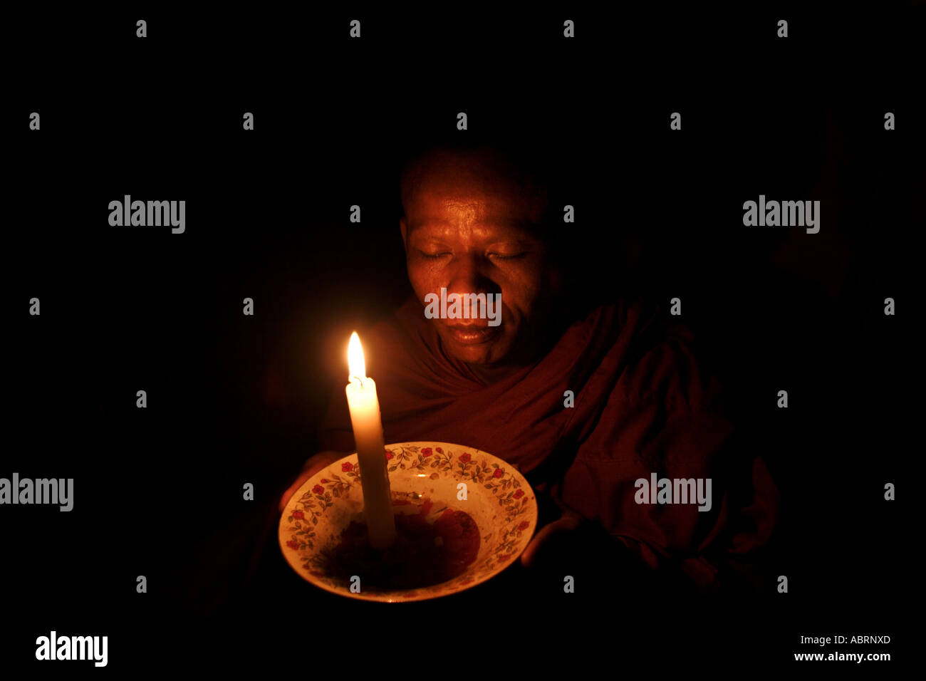A Buddhist monk meditates by candlelight at a temple in Mondulkiri, eastern Cambodia. Stock Photo