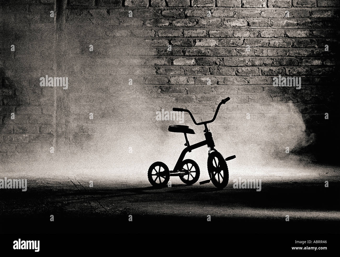 Tricycle against brick wall Stock Photo