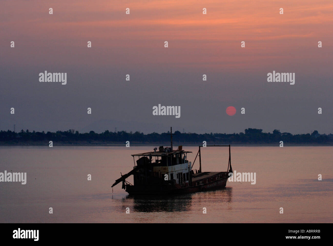 A rusting vessel lies at anchor in the flow of the Mekong  river near Pakse in southern Laos. Stock Photo