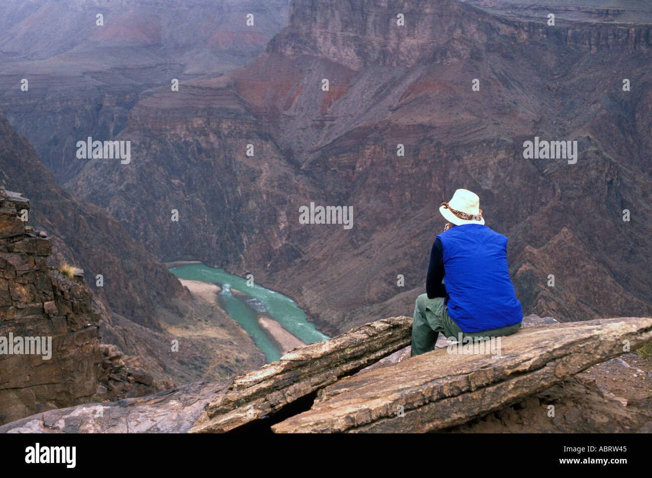 Backpacker Rests Above Colorado River in Grand Canyon Stock Photo