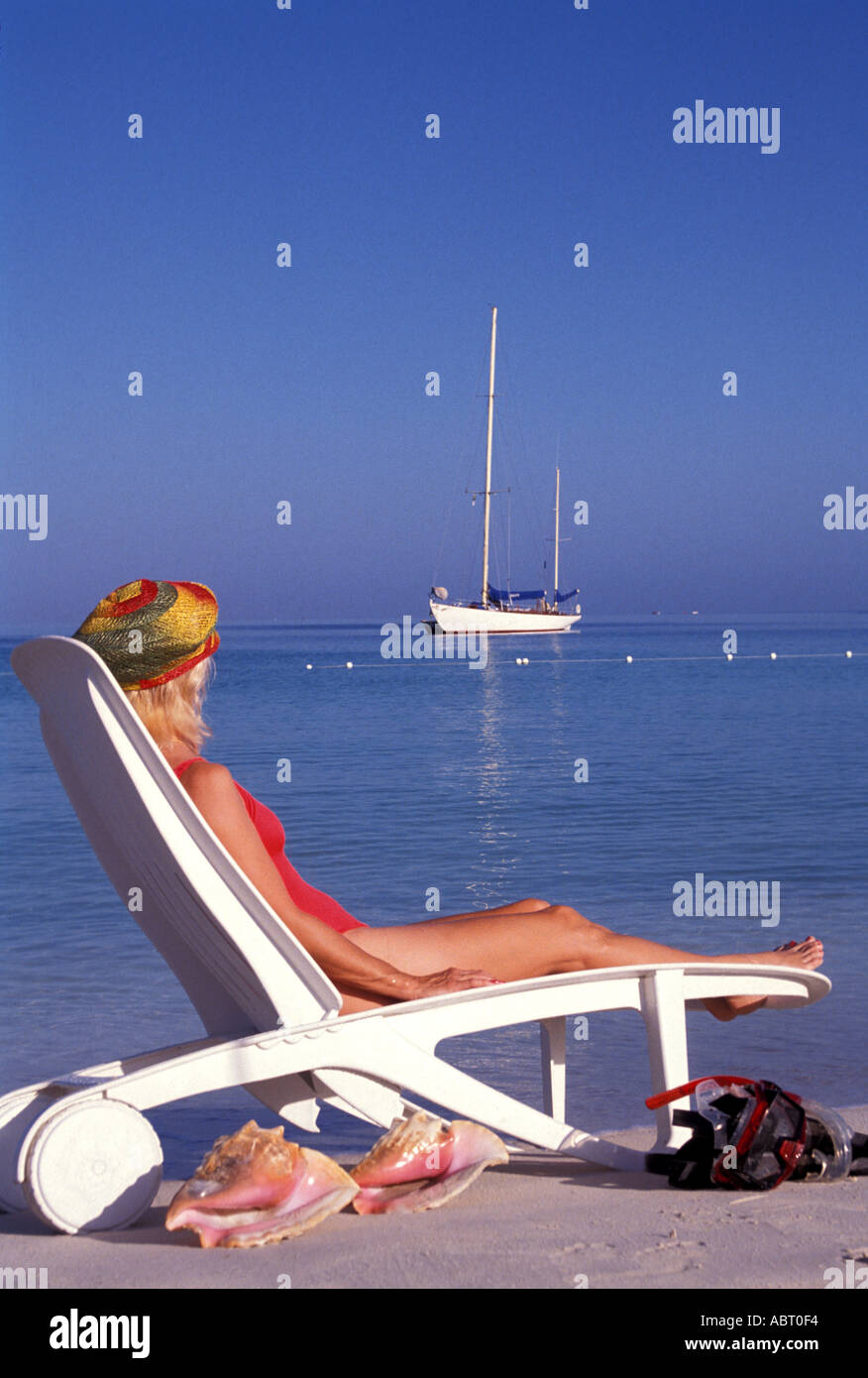 JAMAICA Negril Woman in red bathing suit sitting in beach chair with