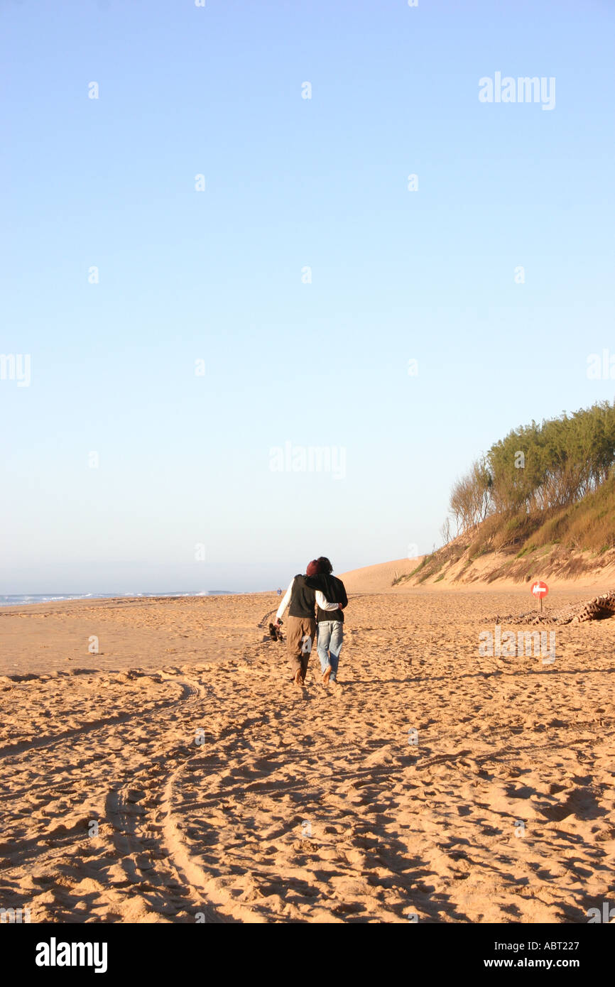 Young couple walking arm in arm on beach Stock Photo