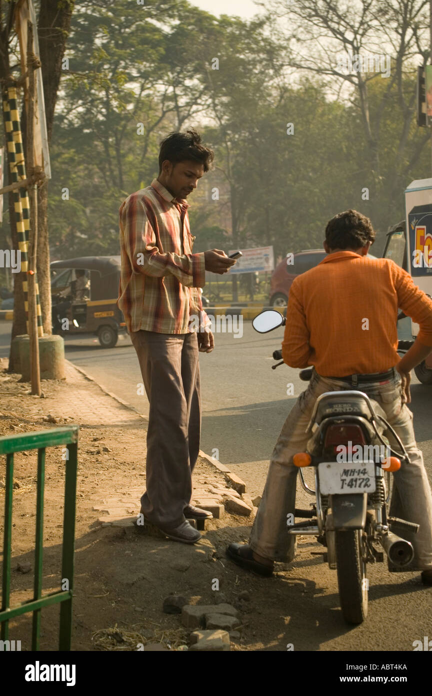 An Indian man using his mobile telephone on a street corner Poona India Stock Photo