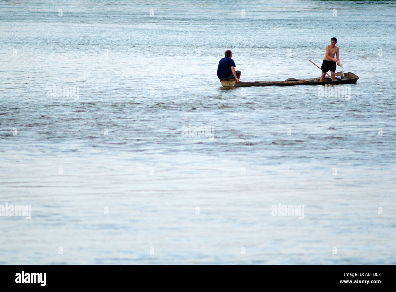 Two Youths Bailing Water From a Small Boat on the River Sava, Bosanski Novi, Bosnia Herzegovina. Stock Photo