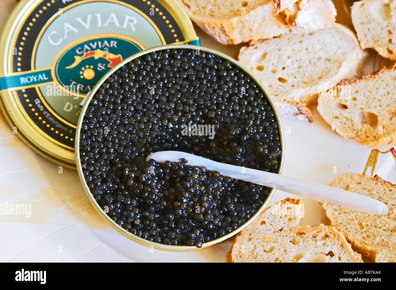 A just open tin of black caviar with slices of bread and a spoon