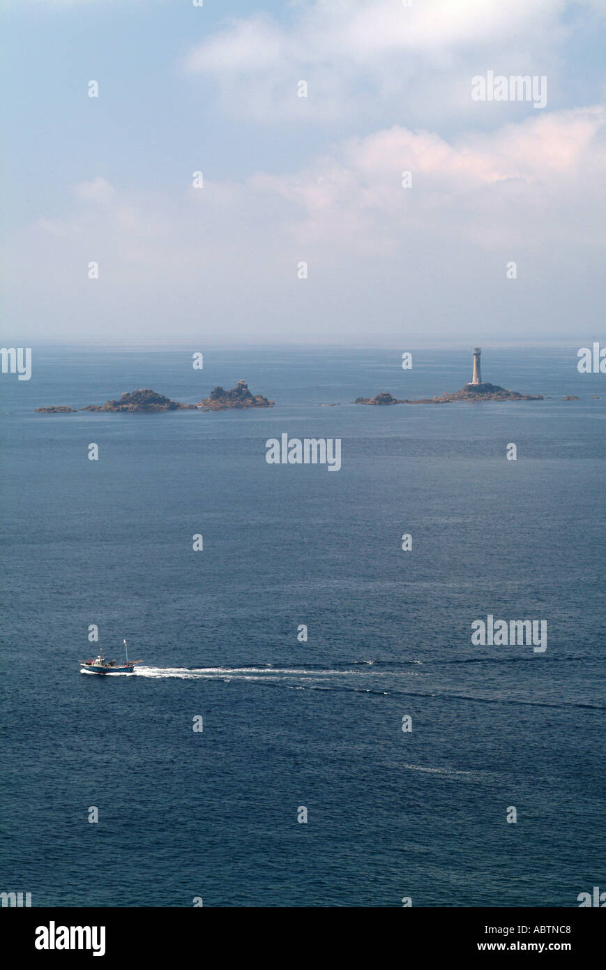 Fishing Boat Passes Longships Lighthouse near Lands End Cornwall England United Kingdom UK Stock Photo