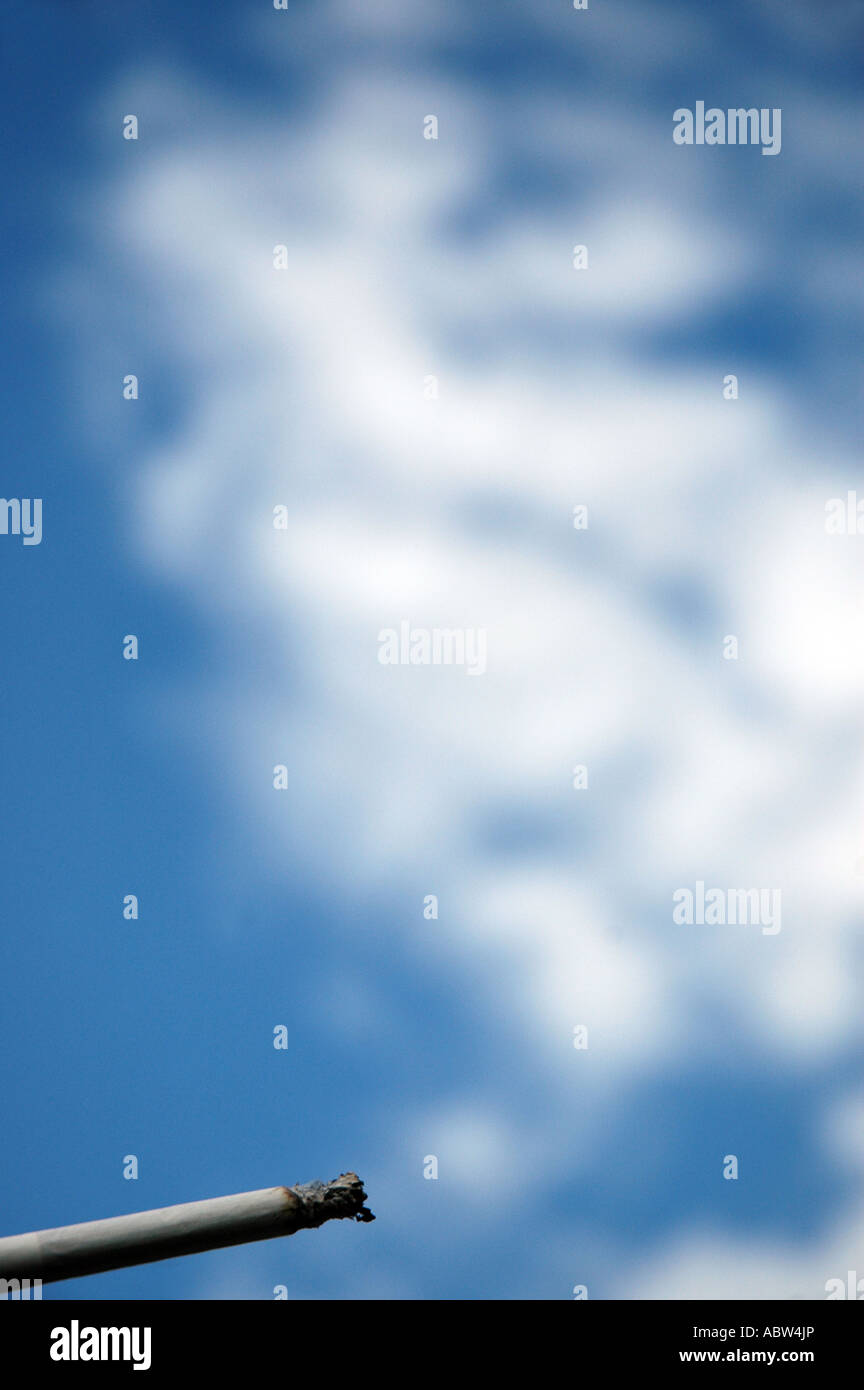 Cigarette against a background of blue sky with white clouds look like