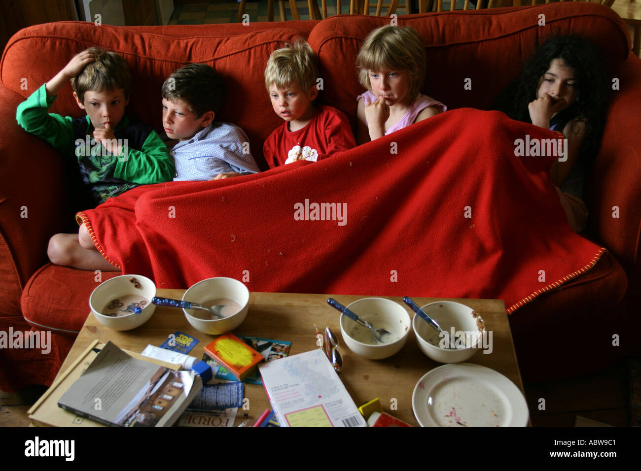 Children watching morning child television shows sitting on a sofa whilst on holiday. Stock Photo