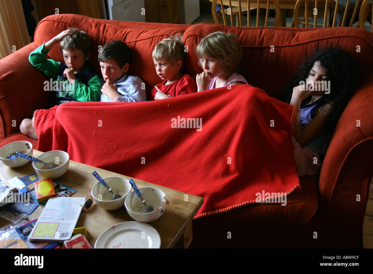 Children watching morning child television shows sitting on a sofa whilst on holiday. Stock Photo