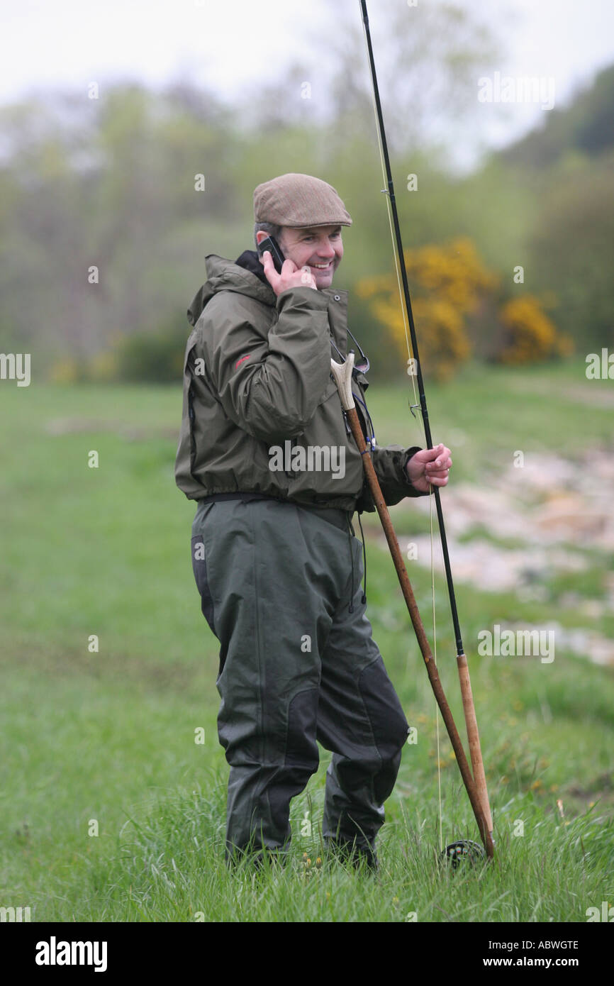 'Salmon fisherman takes a break to talk on a mobile telephone' Stock Photo