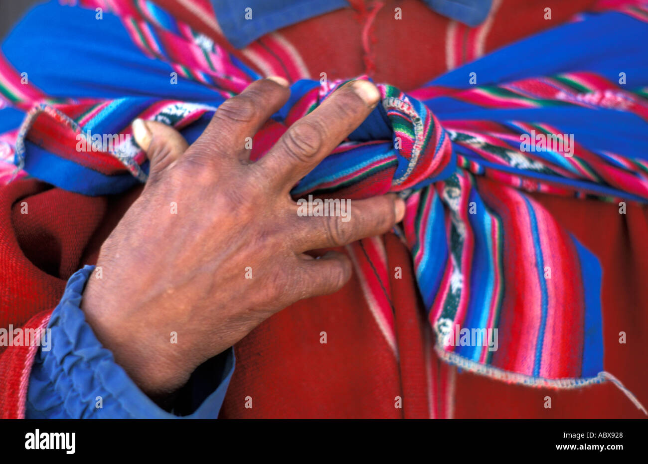 Close up of hands and shawl tied around red poncho of a Quechua speaking man Tarabuco Sunday market Bolivia S America Stock Photo