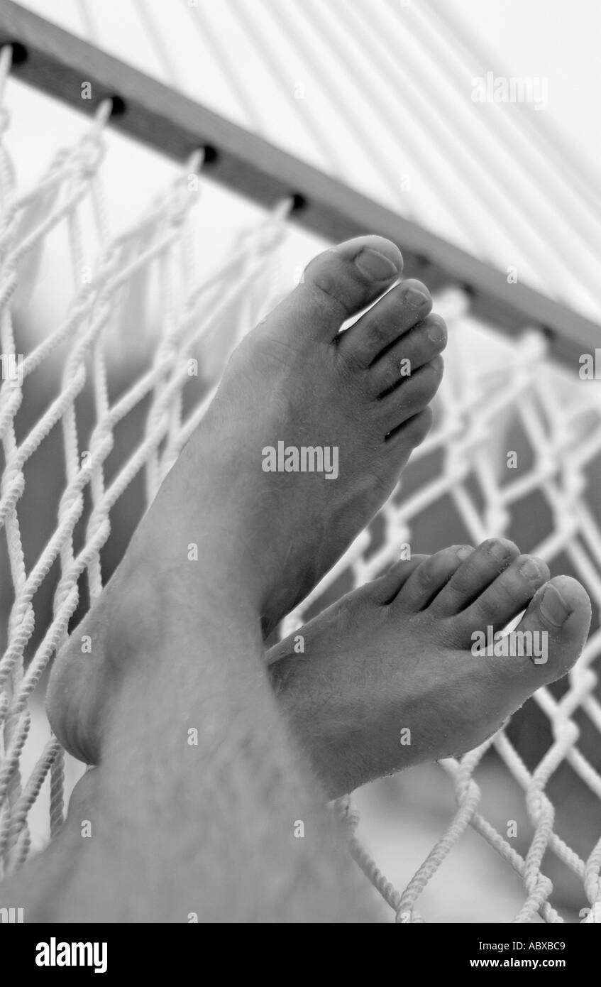 Mans feet on hammock on beach Stock Photo