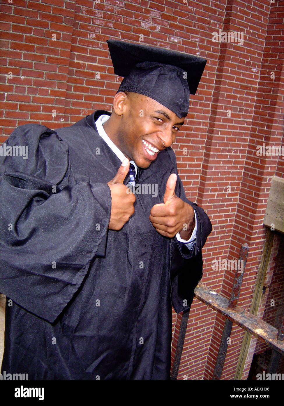 Portrait of a Man Wearing A Graduation Cap And Gown He is Excited and is  Making the Thumbs Up Gesture Stock Photo - Alamy