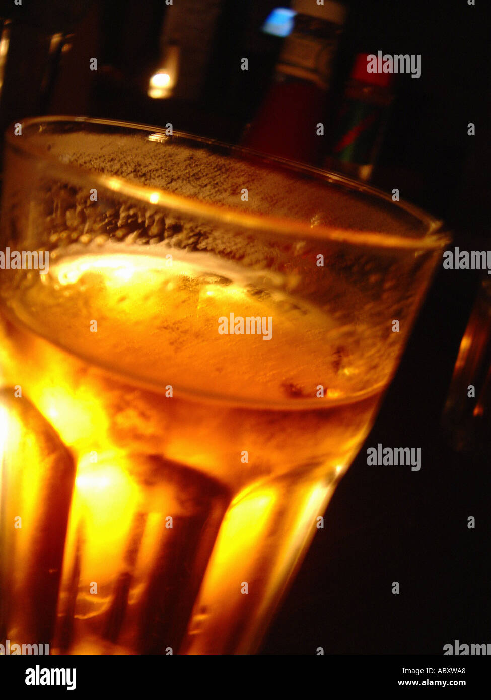 Still Life of a Closeup of a Glass Pint of Beer Backlit by a Candle Stock Photo