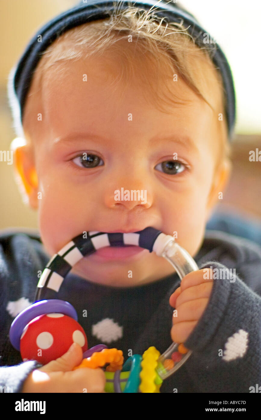 Baby boy chewing on colorful teething toy Stock Photo