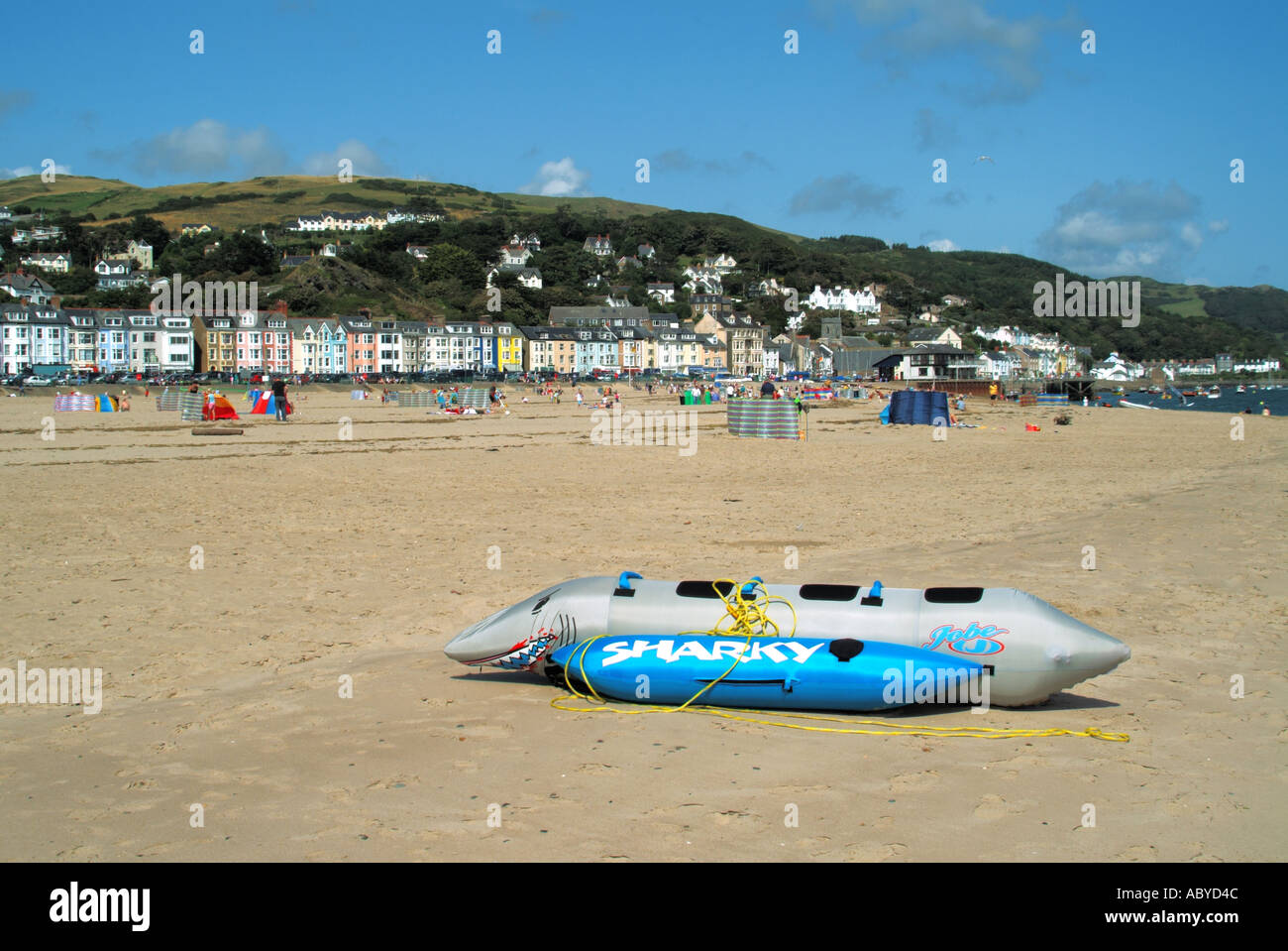 People on family holiday sandy summer beach with homes hotel & guest house accommodation hillside backdrop Aberdyfi Aberdovey Gwynedd North Wales UK Stock Photo