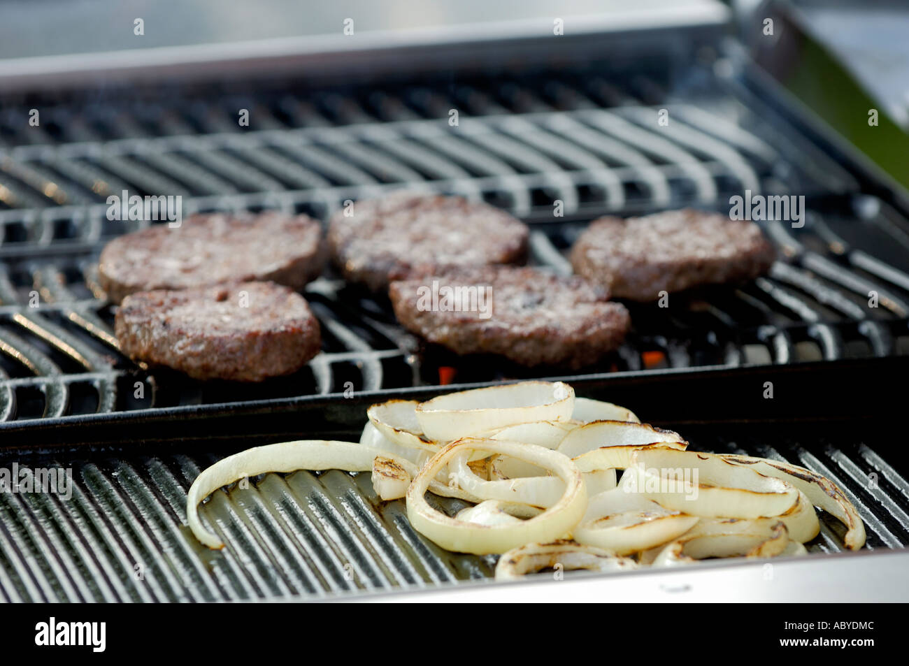 cooked burgers on a gas BBQ with onions Stock Photo Alamy
