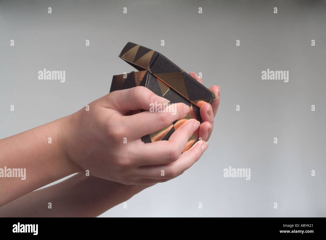 A partially opened gift box is carefully clutched in hands Stock Photo