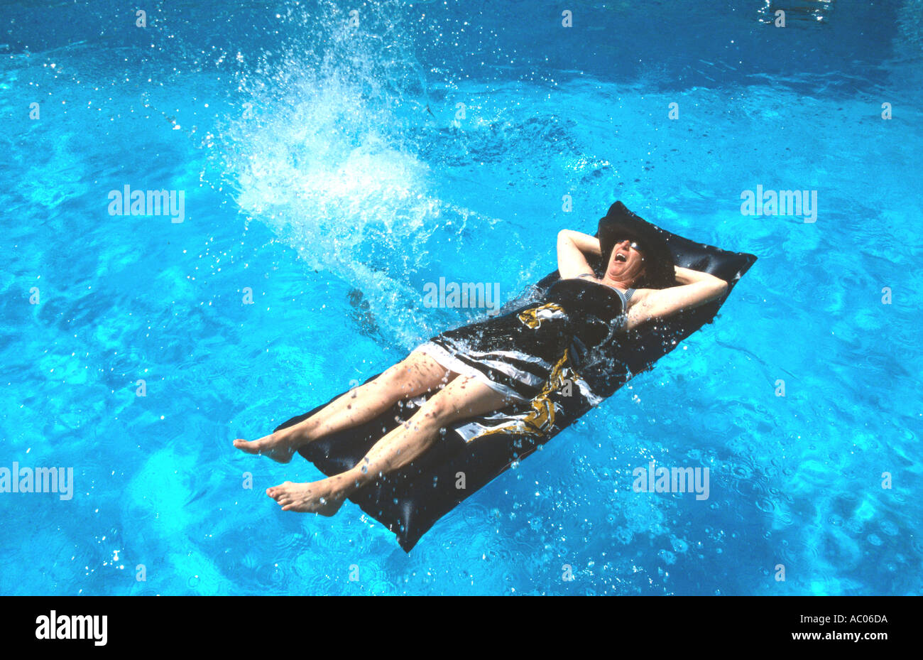 Woman on an inflatable airbed is splashed villa swimming pool Provence South of France Stock Photo