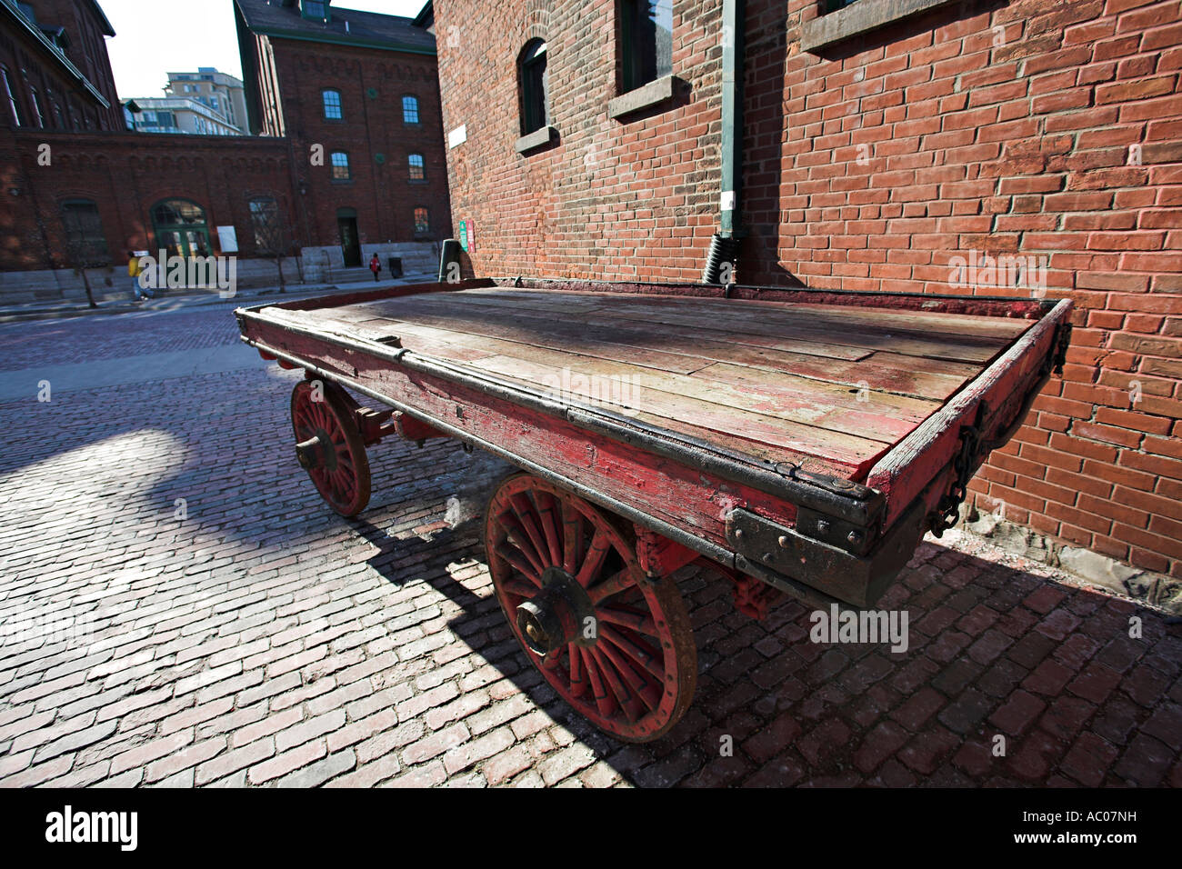 Distillery Wagon. An old red wooden industrial waggon wagon on a cobblestone street with a red brick wall behind Stock Photo