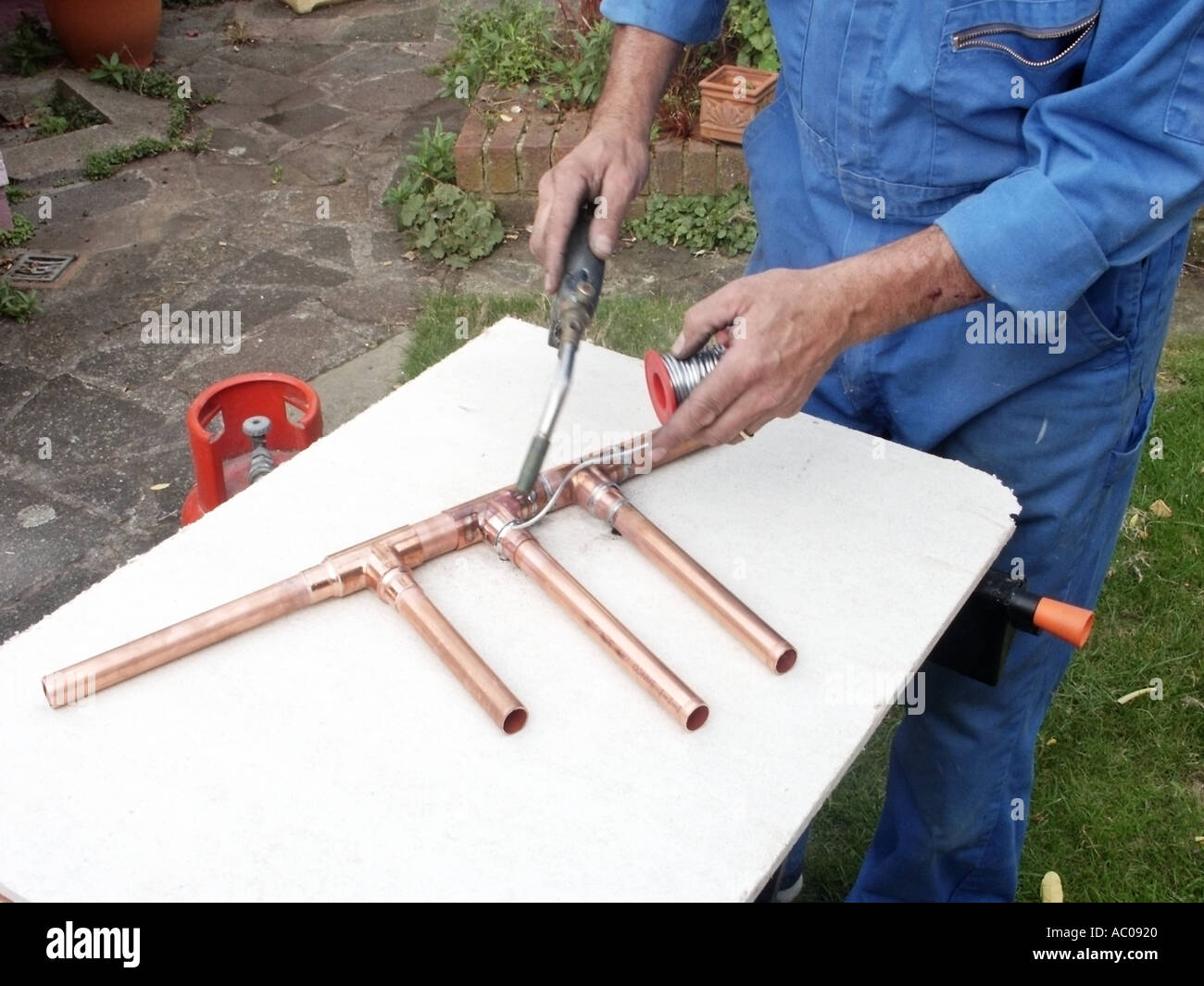 Close up of plumber using a propane gas torch to heat solder to make a