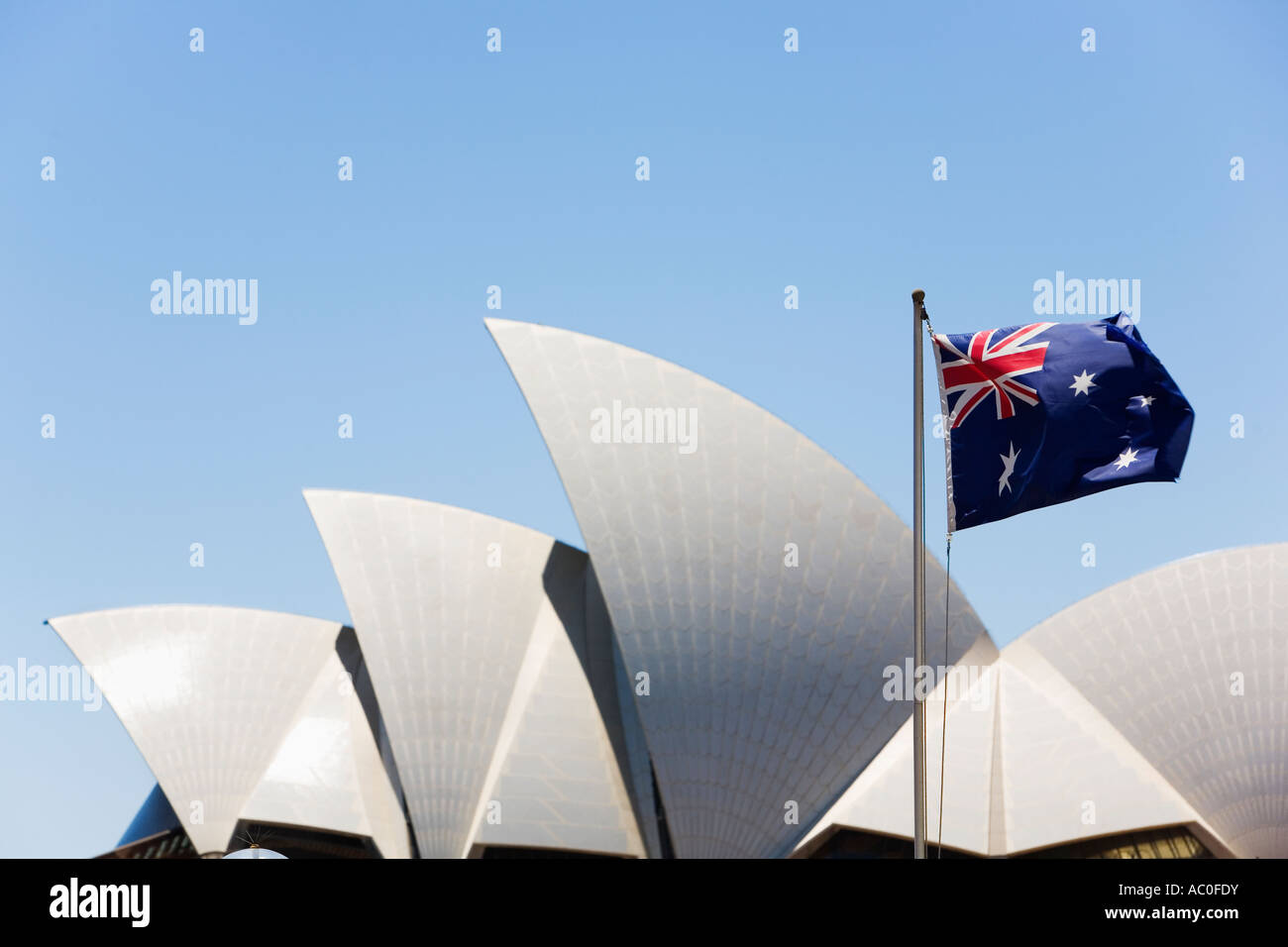 An Australian flag flutters in front of the arched rooftops of the Sydney Opera House Stock Photo