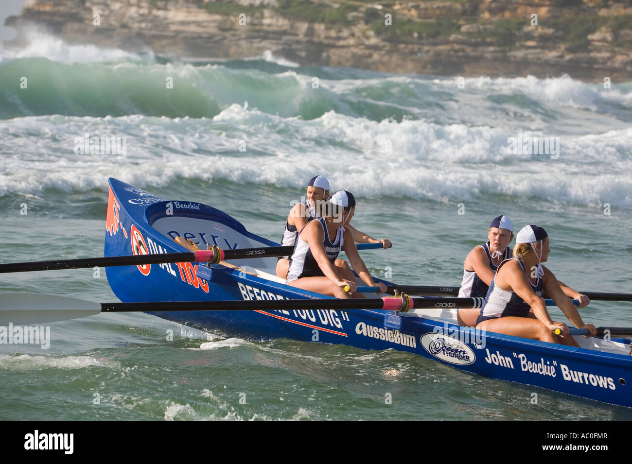 A female surfboat crew rows their boat into the surf at Bondi Beach in Sydney Surfboats were once used for beach rescues Stock Photo