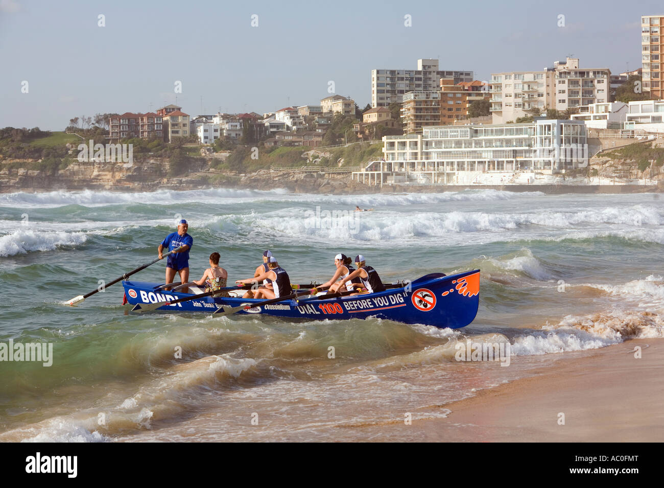 A female surboat crew bring their craft onto the shore at Bondi Beach Stock Photo