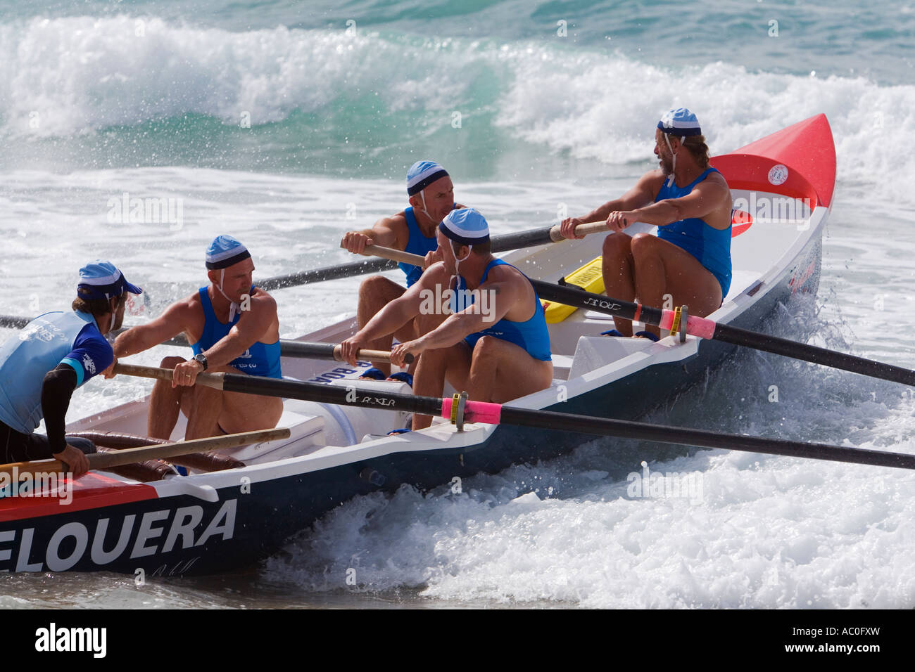 A surfboat crew battles to row out through the waves during a race at Cronulla Beach Stock Photo