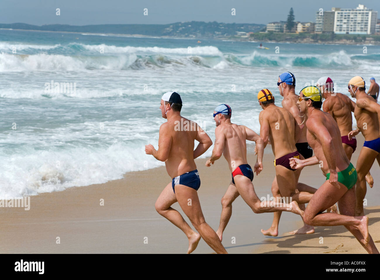 Lifesavers wearing the colours of their respective clubs sprint to the water during a swimming race at the New South Wales Stock Photo