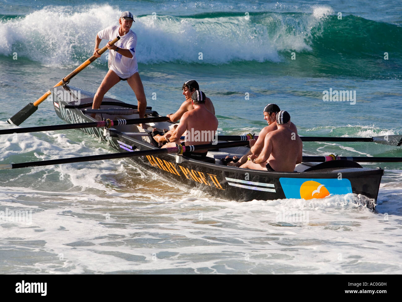 A surfboat crew battles through the waves at Cronulla Beach in Sydney Stock Photo