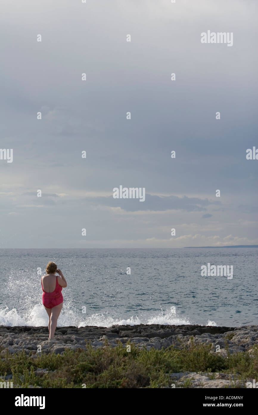 Woman in swimsuit, taking a photo on rocky shore, Puglia, Italy Stock Photo