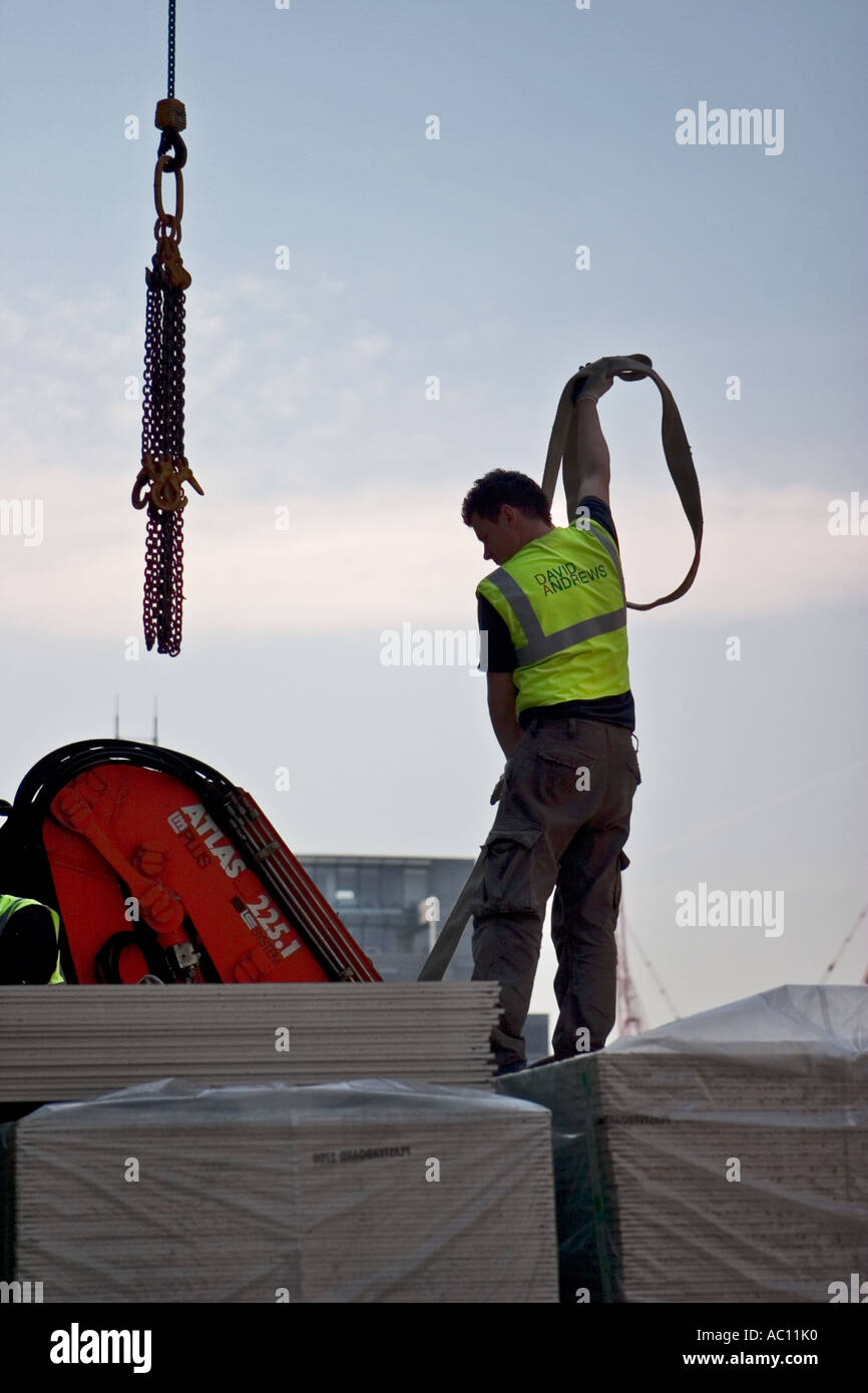 Construction worker unhooks material from crane Stock Photo