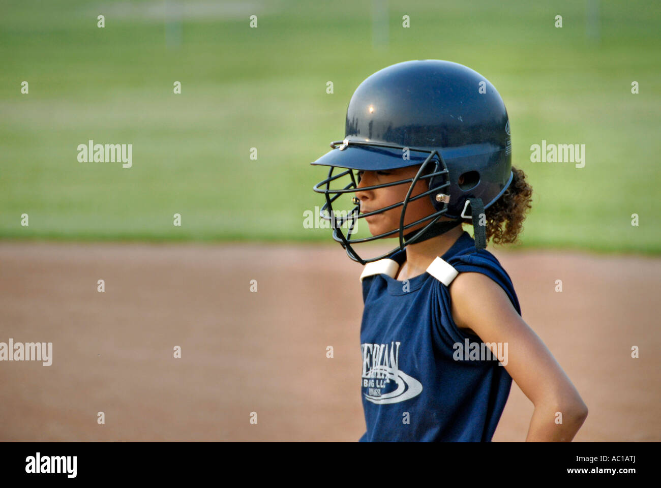 Girl baseball player wearing a protective helmet with a face guard