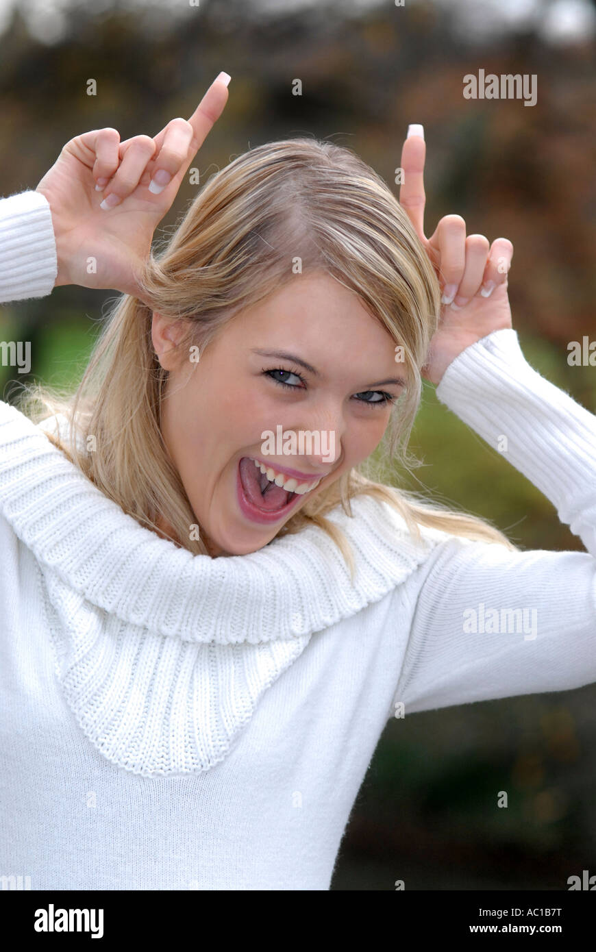 Woman making horns with fingers mouth open portrait Stock Photo