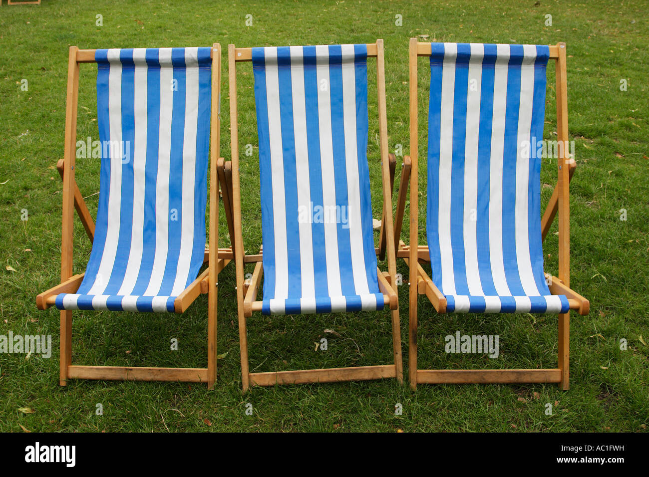 three blue and white stripped empty deckchairs in a park london england uk Stock Photo