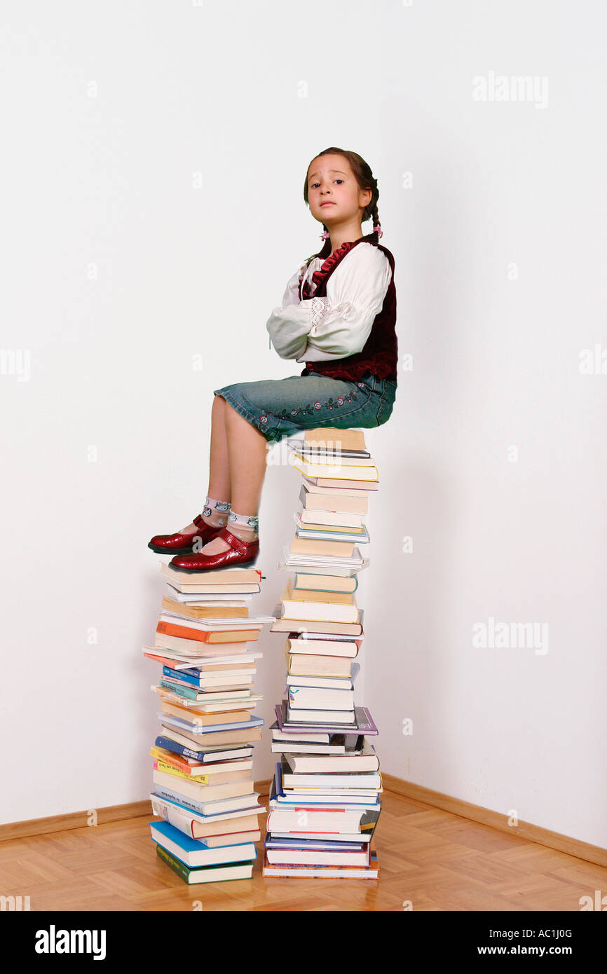 Girl with braids sitting on on pile of books Stock Photo - Alamy