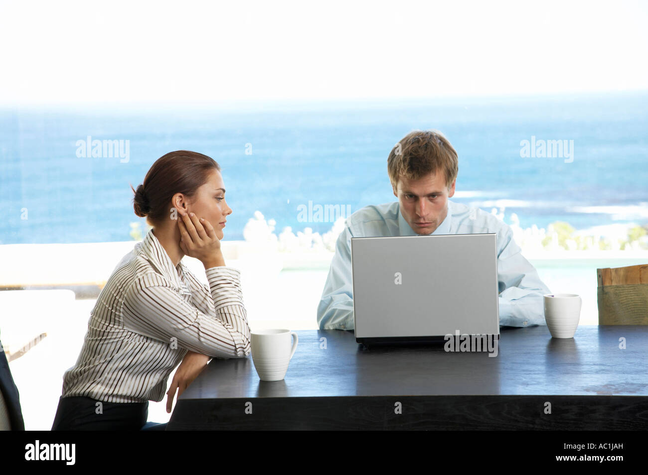 Couple sitting at table, man using laptop Stock Photo