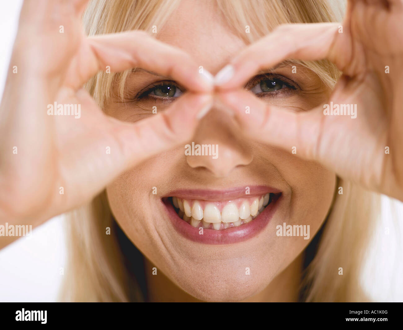 Woman looking through fingers, smiling Stock Photo
