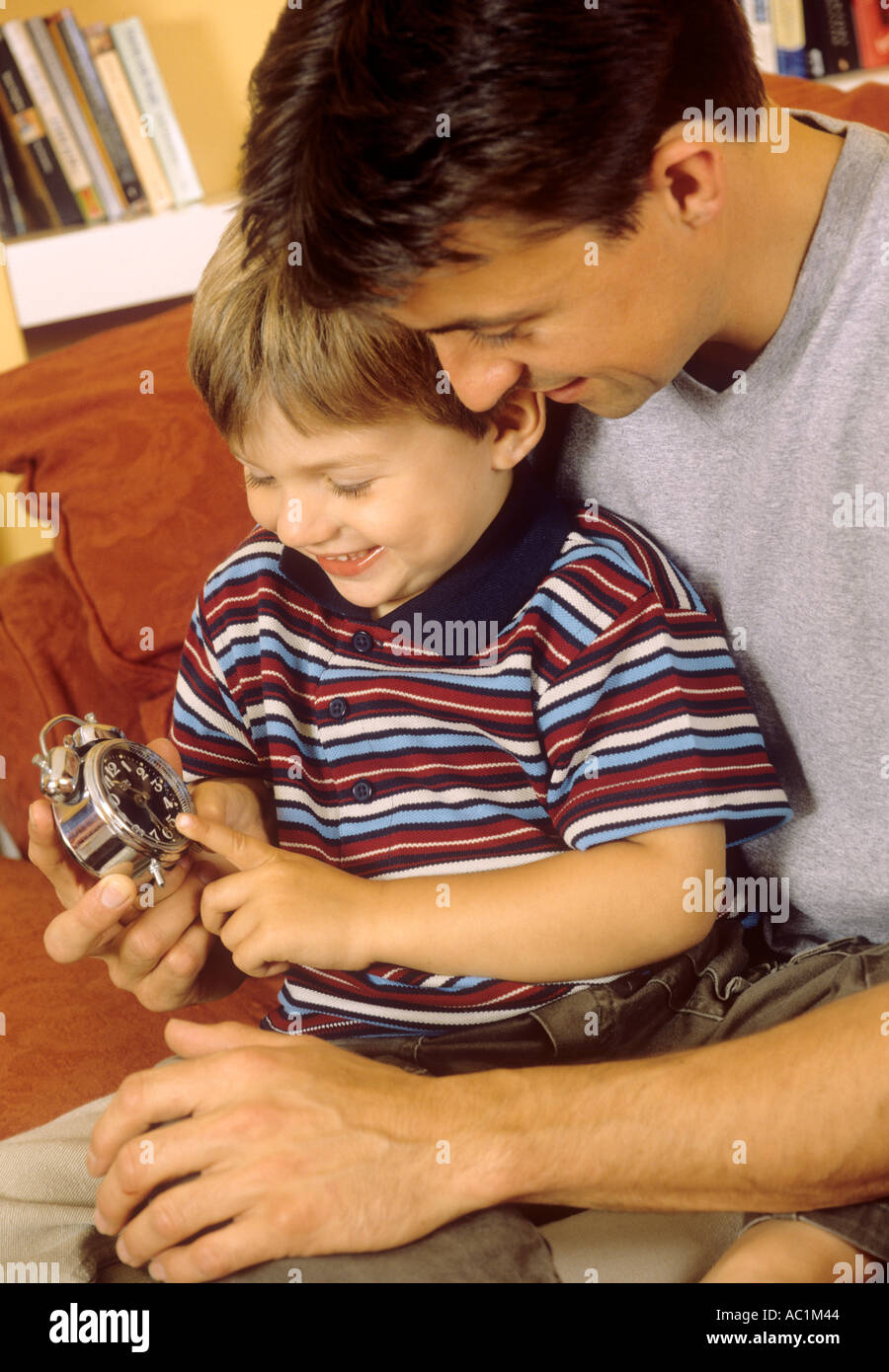 Father with his son teaching him to tell the time using an alarm clock Stock Photo Alamy