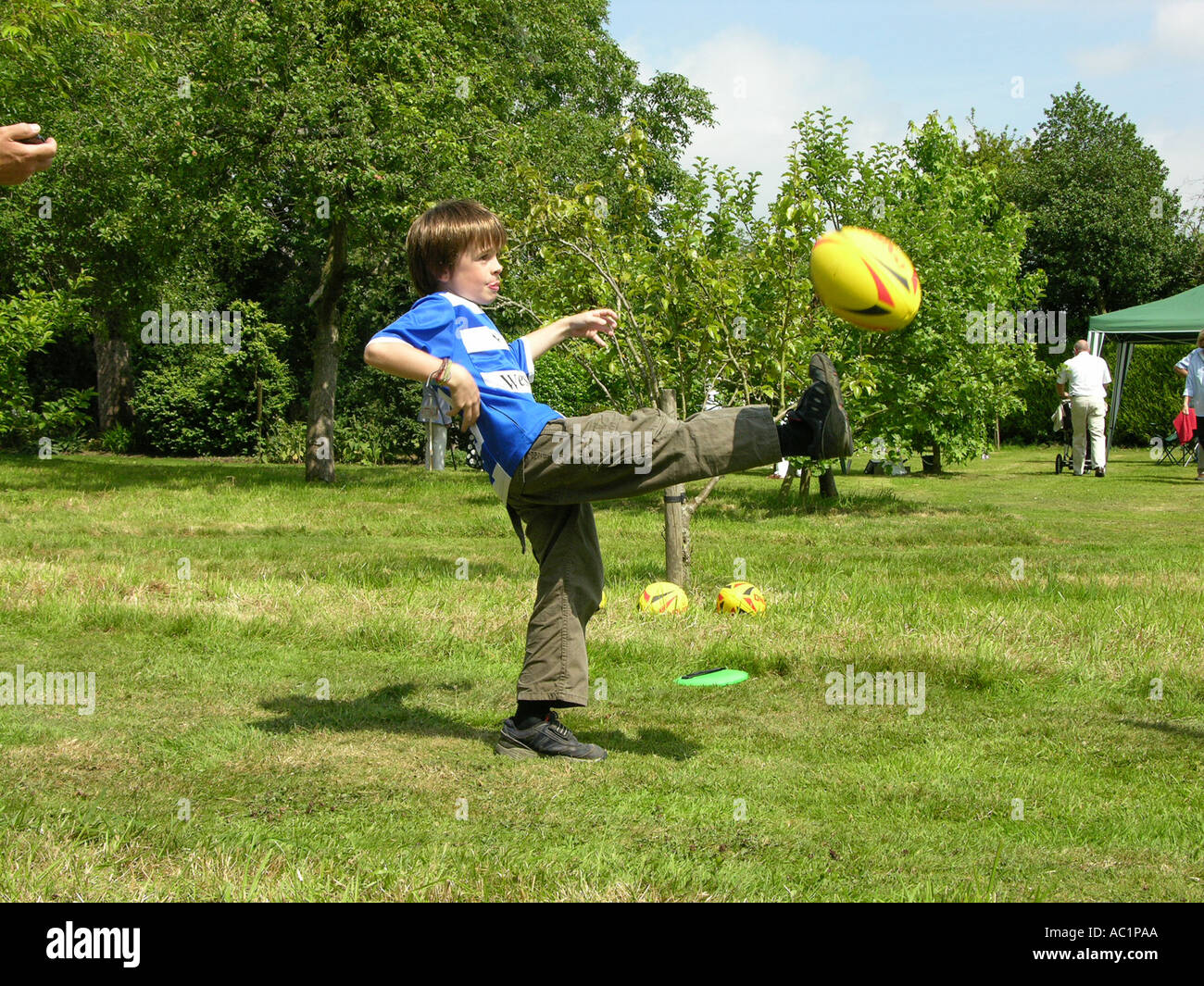 Boy kicking rugby ball in garden Stock Photo