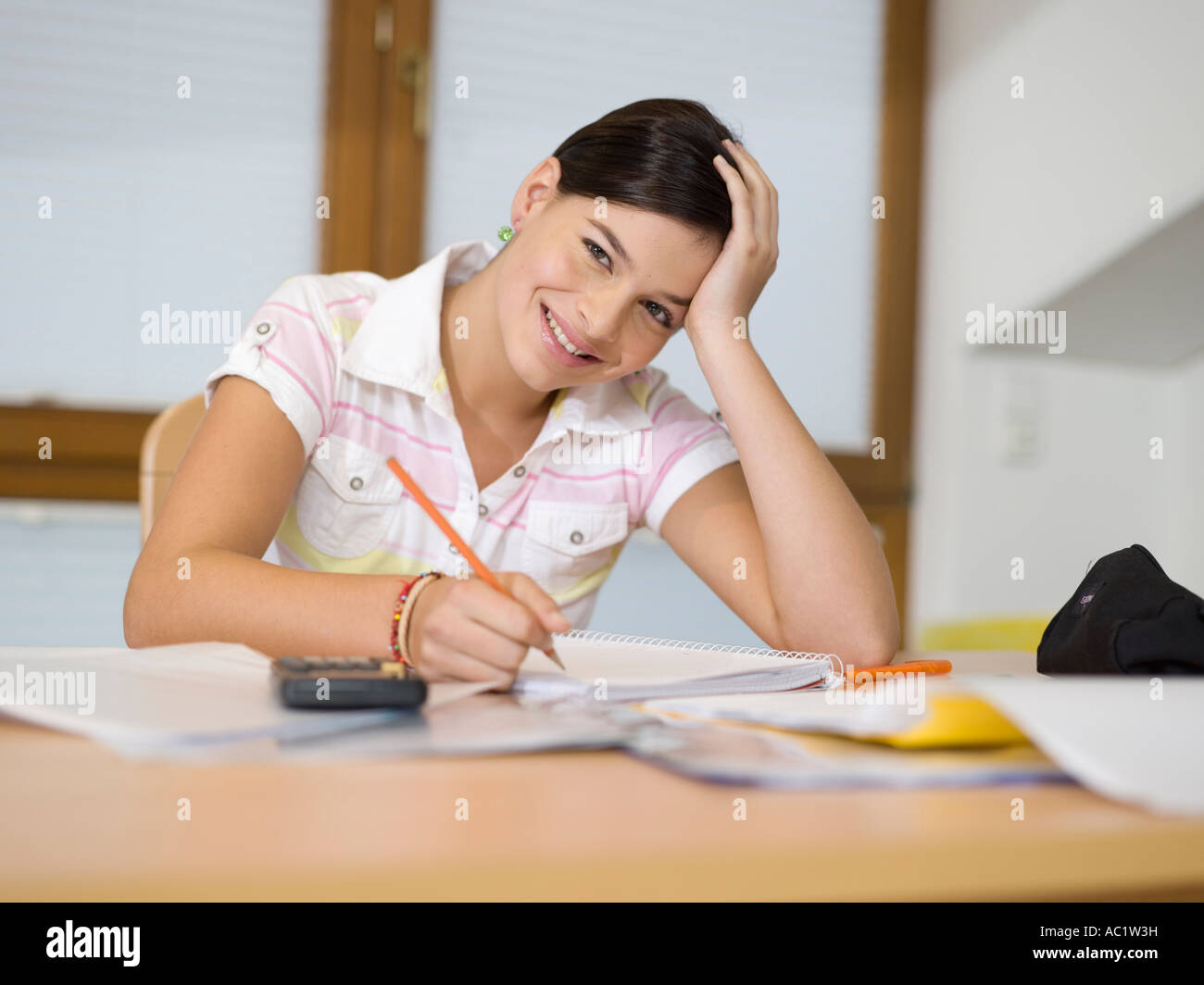 Young woman sitting on desk, writing Stock Photo - Alamy