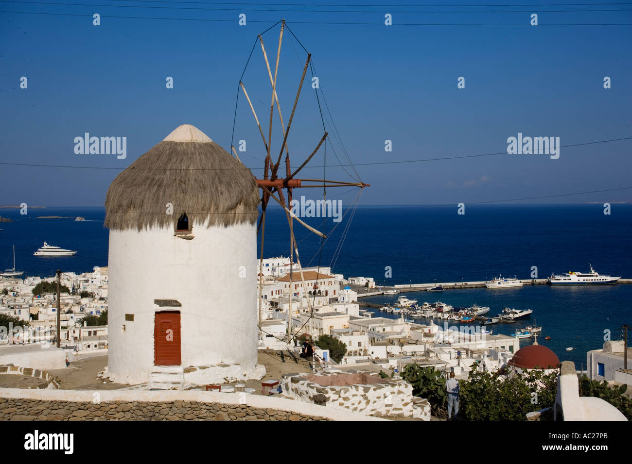View from hill with famous traditional windmill over the town to the sea with ships Mykonos Town Mykonos Greece Stock Photo